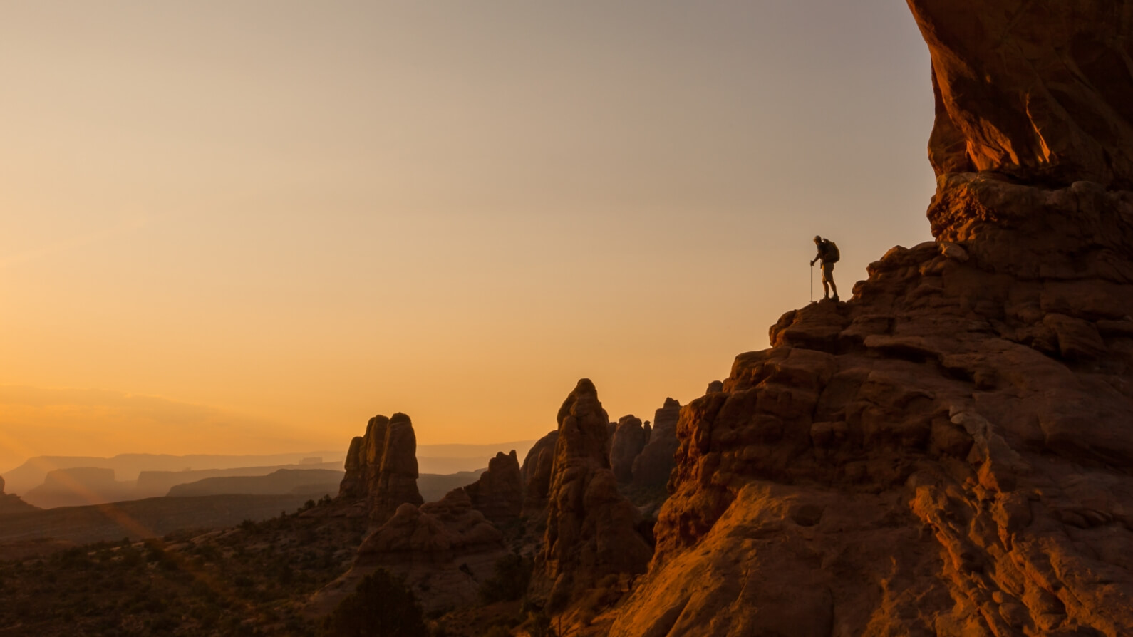 A hiker overlooks Moab's desert beauty from a rocky mountainside near Lionsback Resort.