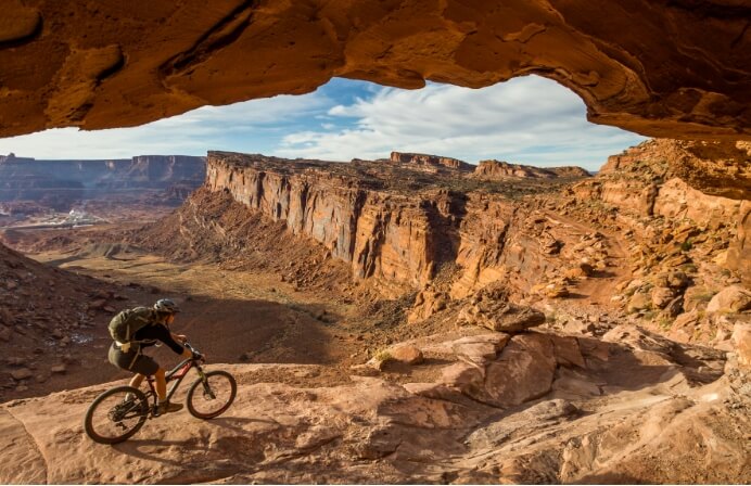 A person mountain biking under an arch near Lionsback Resort.