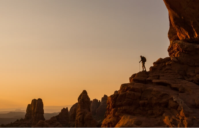 A hiker standing on a rocky mountainside experiencing Moab's beauty near Lionsback Resort.