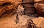 Two people hiking through red rocks and slot canyons in Moab near Lionsback Resort.